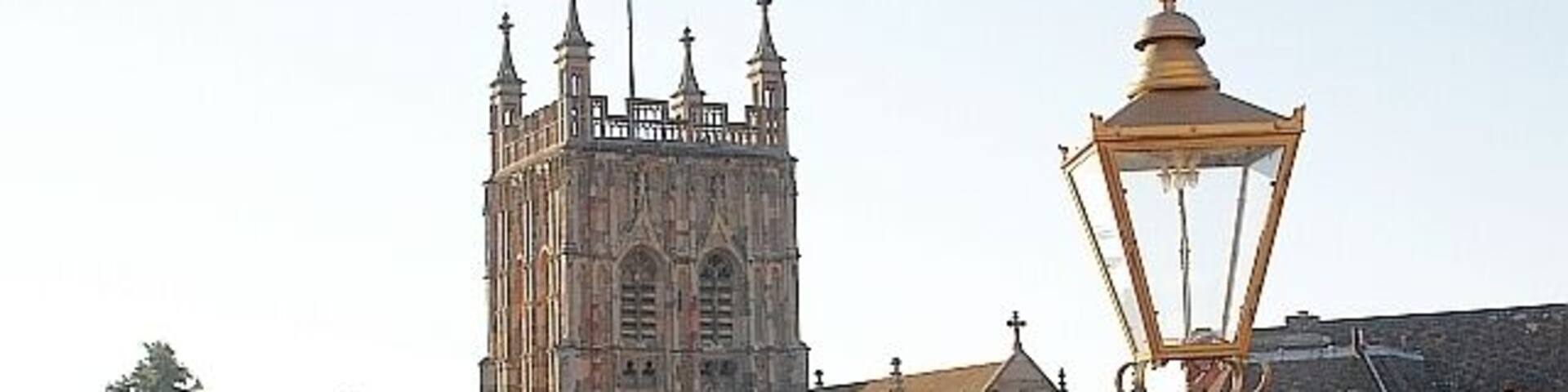 A historic building with a tall tower, a street lamp, and a flower basket.