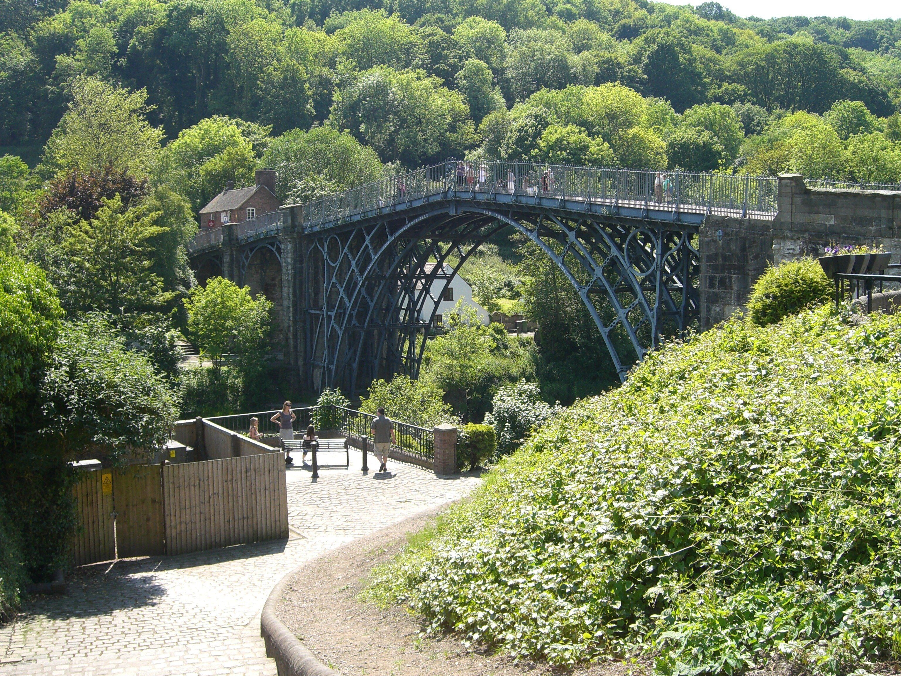 A stone bridge over a river, surrounded by lush greenery and trees.