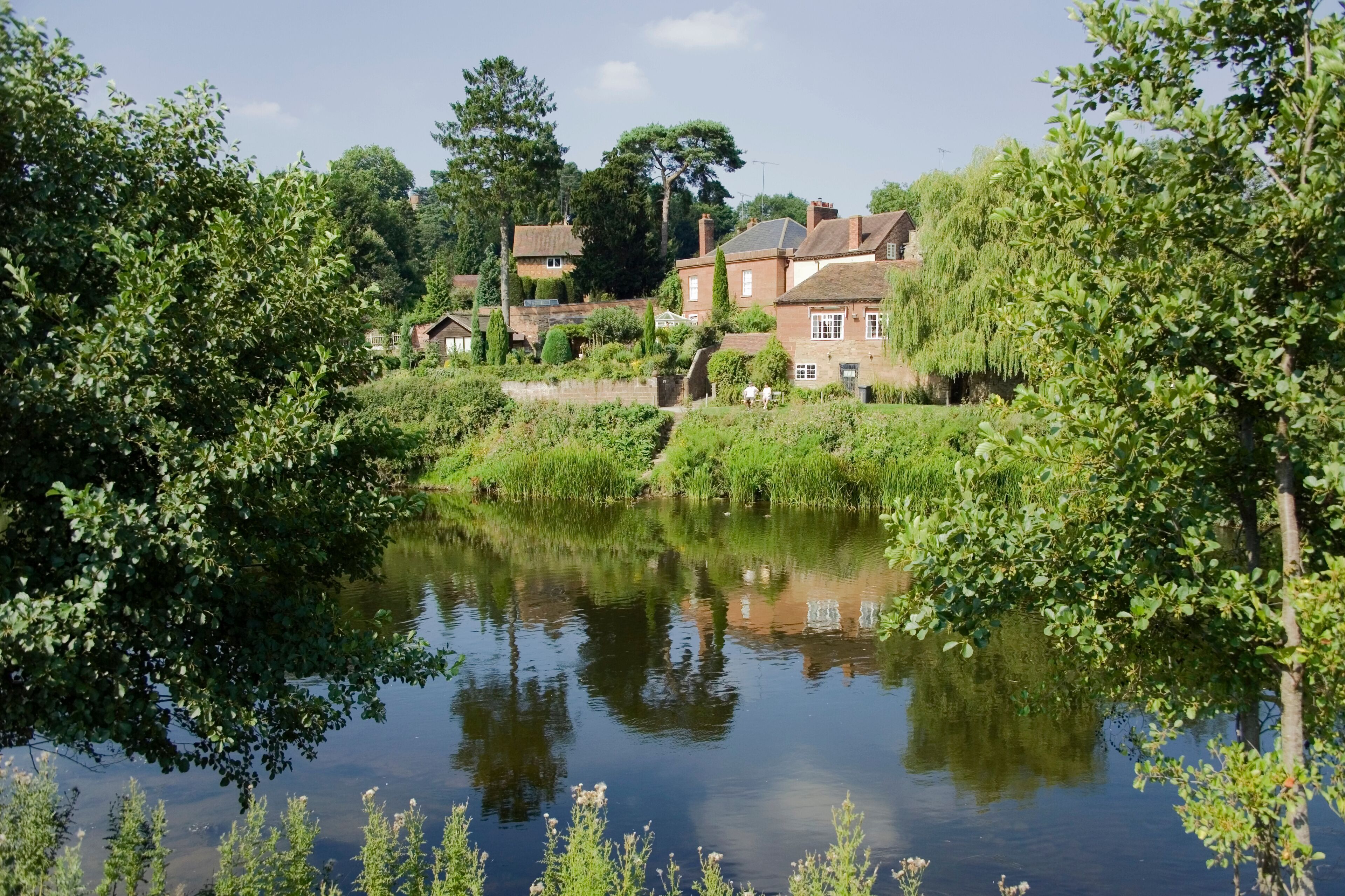 A calm river with reflections of trees and houses.