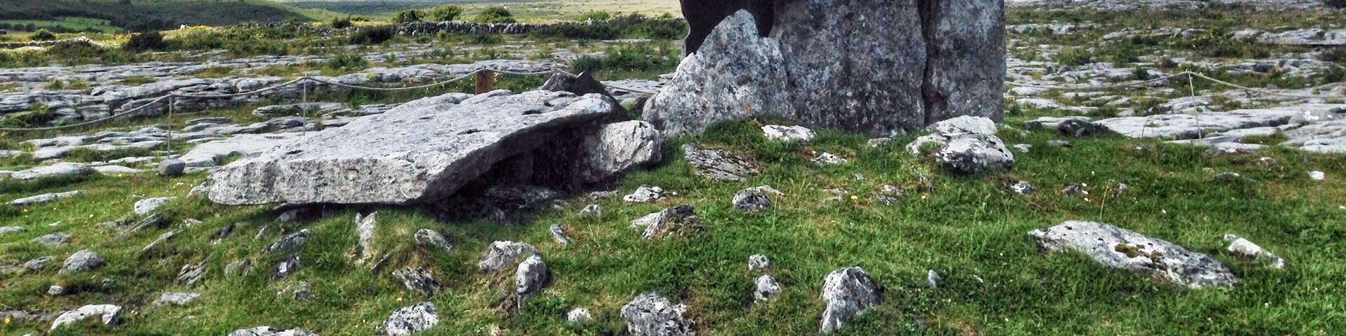 A standing stone in a grassy field with a cloudy sky.