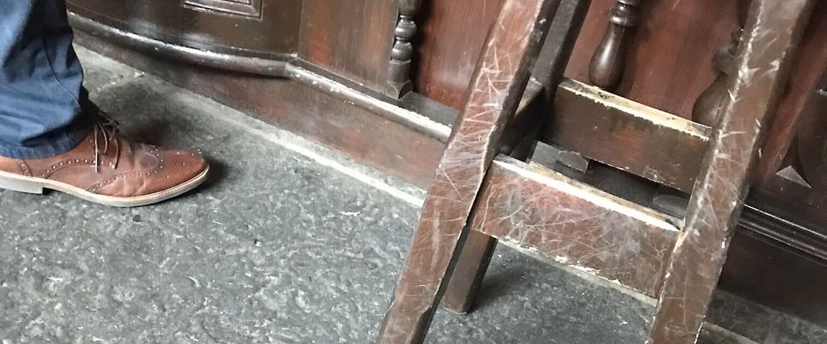 A wooden ladder leaning against a door with a textured floor.