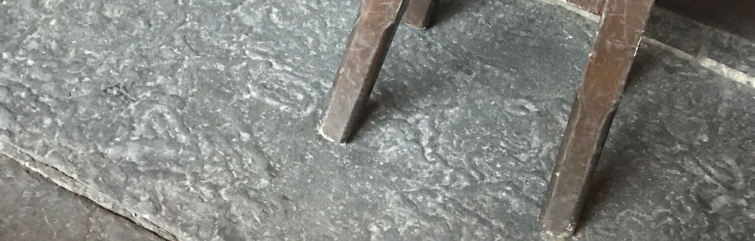A wooden ladder leaning against a door with a textured floor.