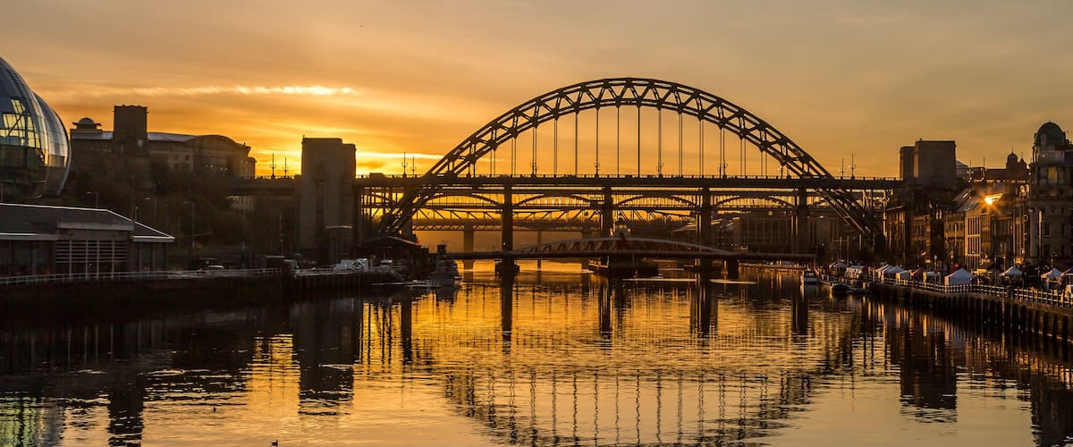 The Tyne Bridge in Newcastle at sunset, reflecting in the almost still River Tyne beneath