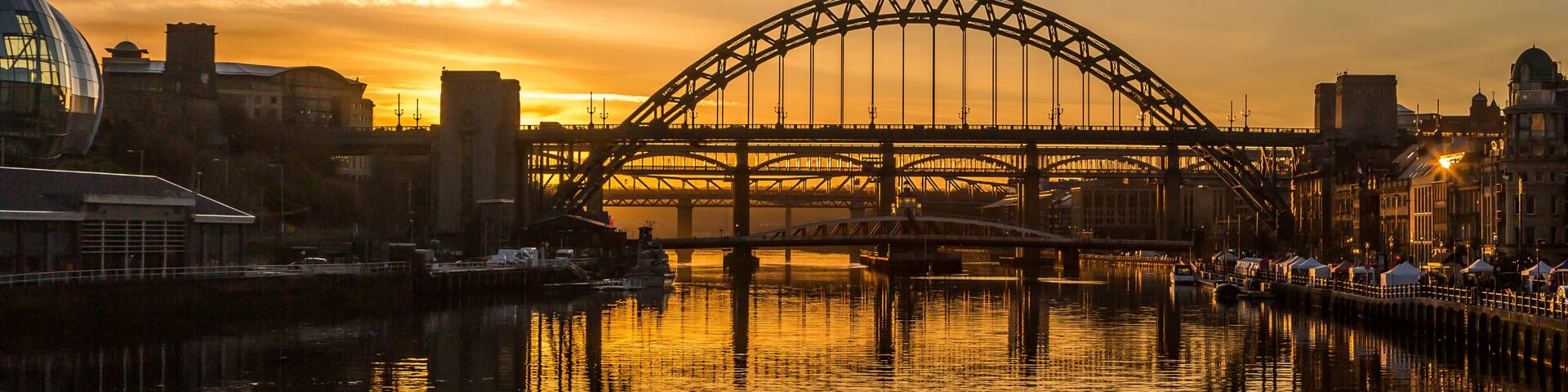 The Tyne Bridge in Newcastle at sunset, reflecting in the almost still River Tyne beneath