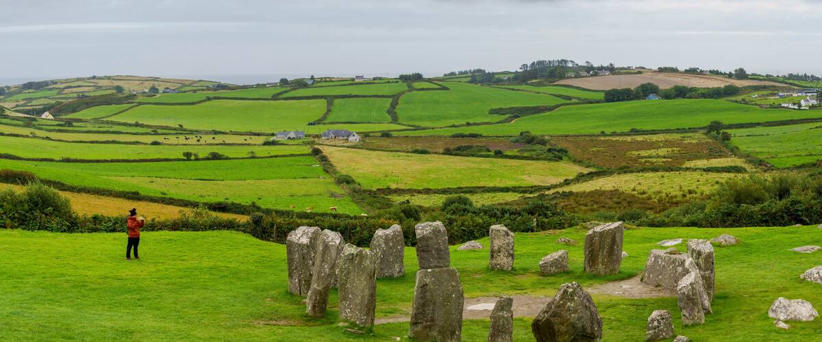 A stone circle in a lush green field with rolling hills in the background.