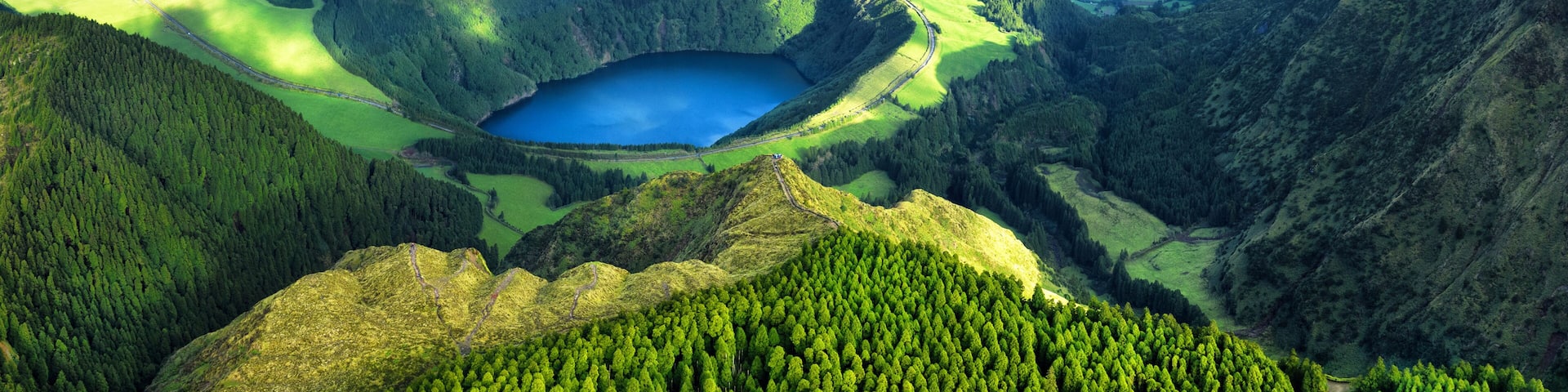 A mountainous landscape with a large lake surrounded by dense forests and rolling hills.