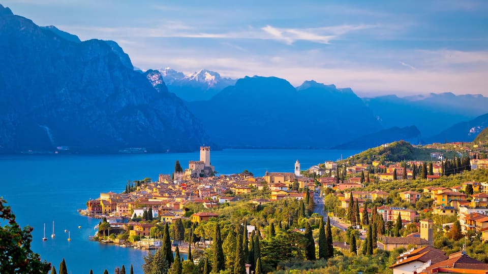 A coastal town with a castle, mountains, and a lake.