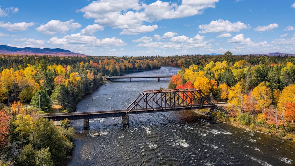 Autumn colors on the river at Moosehead Lake, Maine - train trestle