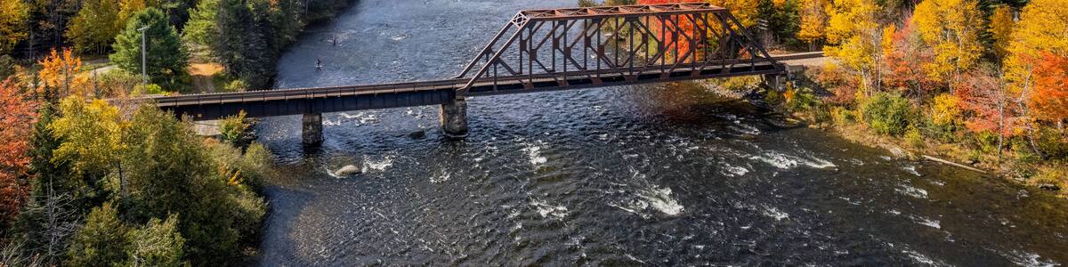 Autumn colors on the river at Moosehead Lake, Maine - train trestle