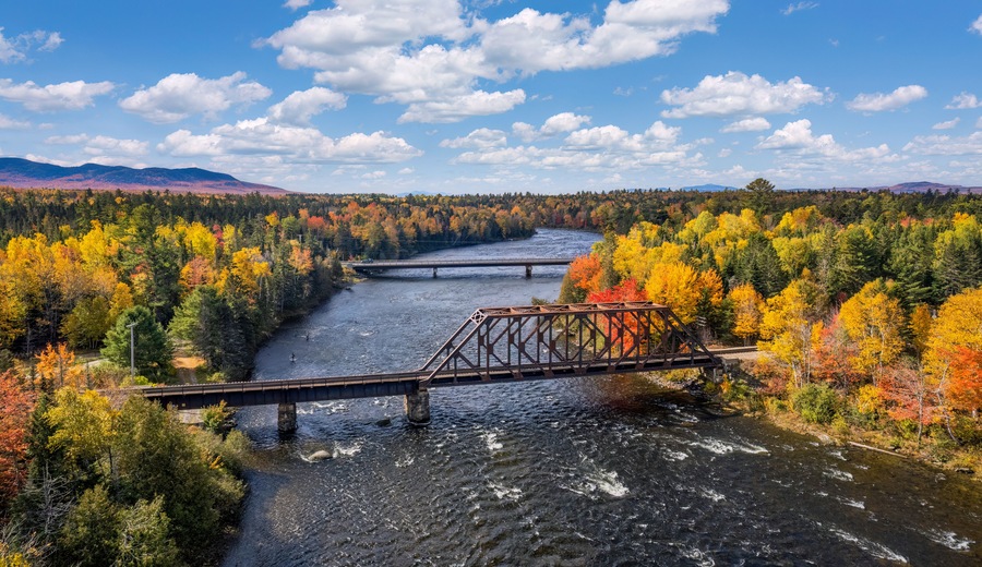 Autumn colors on the river at Moosehead Lake, Maine - train trestle