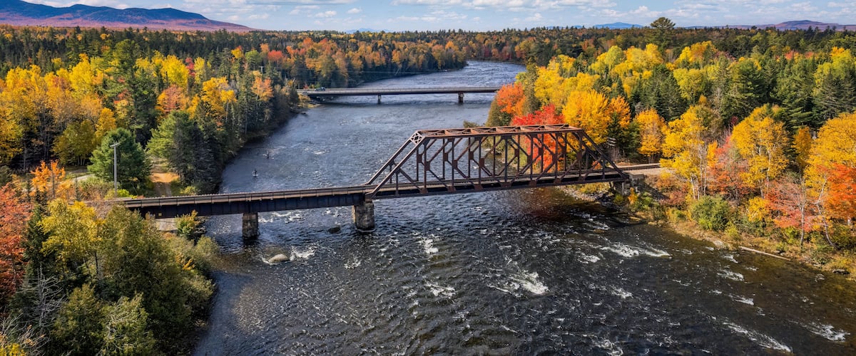 Autumn colors on the river at Moosehead Lake, Maine - train trestle