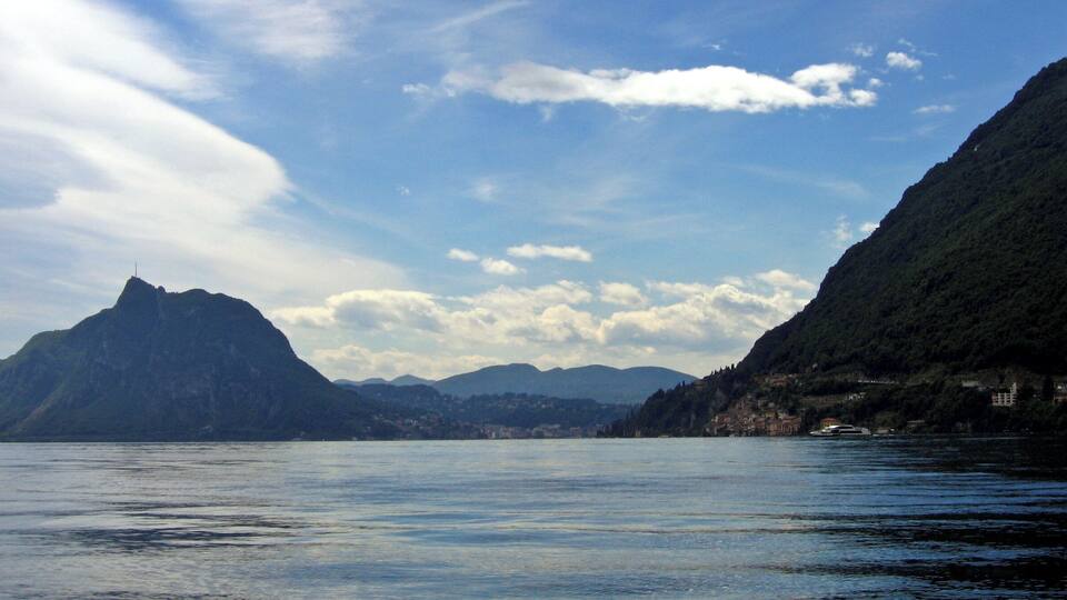A calm lake with mountains in the background and a clear sky.