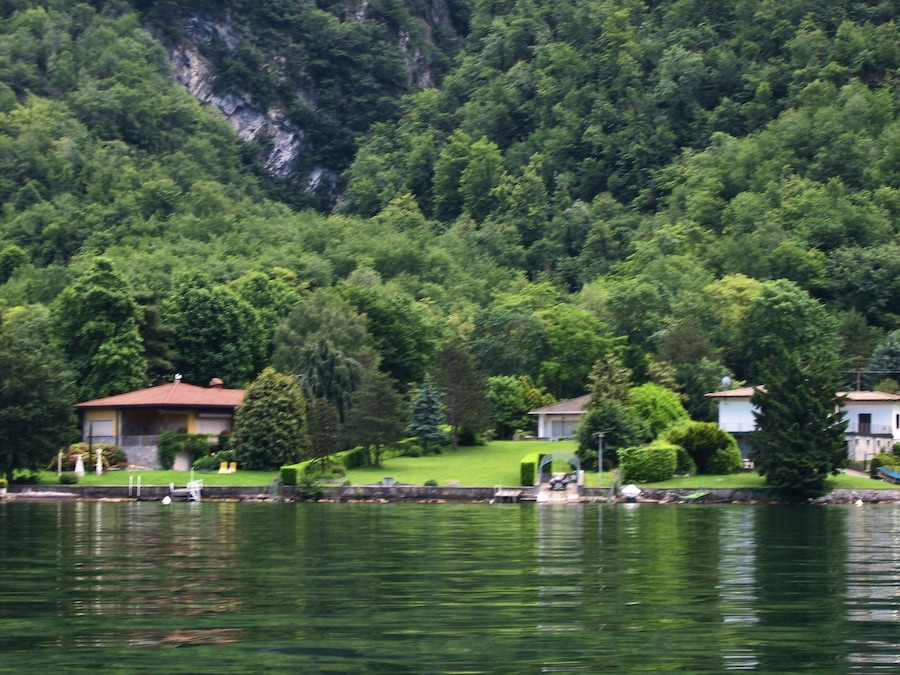Ein See mit Häusern und dichtem Wald.