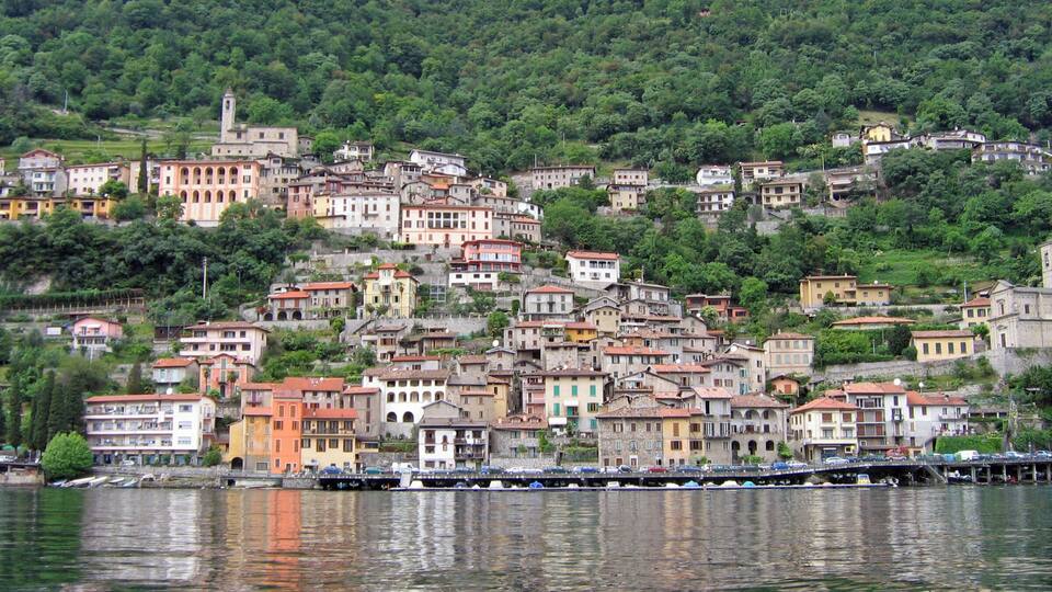 A hillside town with buildings reflecting on the water.