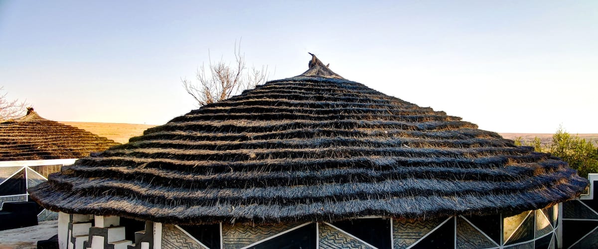 A traditional thatched-roof structure with geometric patterns on its walls.