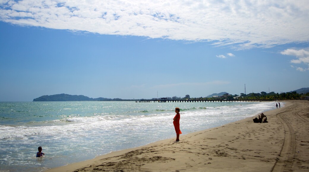 Tela featuring a sandy beach and swimming as well as a small group of people