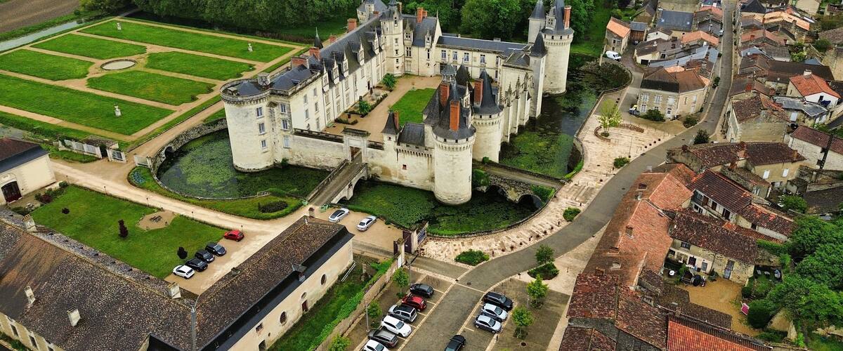 A historic castle surrounded by lush greenery and a small village.