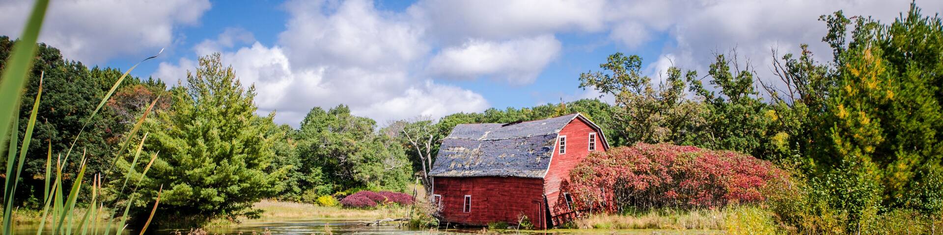 An abandoned red sinking barn sinks into a lake near Zimmerman, Minnesota