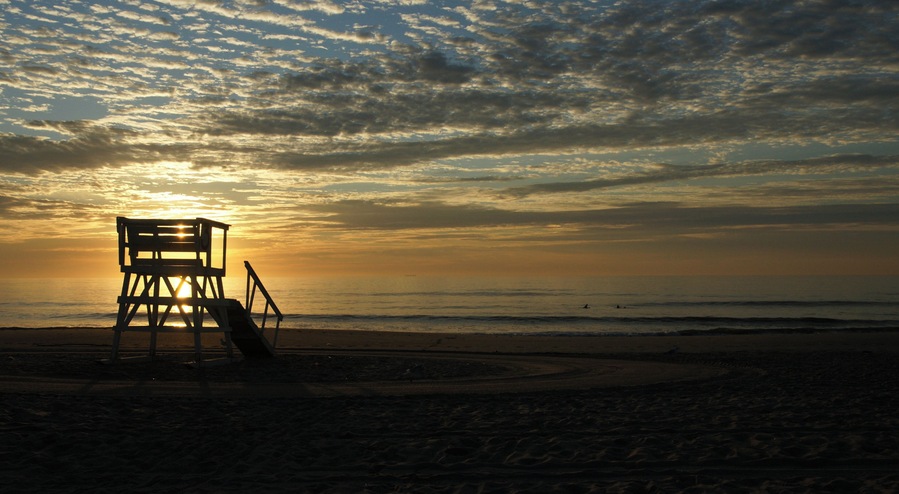 Sunrise over silhouetted beach lifeguard station at New Jersey shore town of Sea Girt.