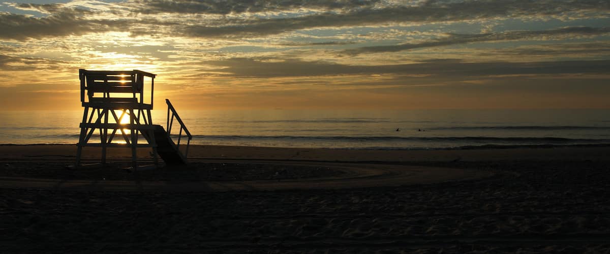 Sunrise over silhouetted beach lifeguard station at New Jersey shore town of Sea Girt.