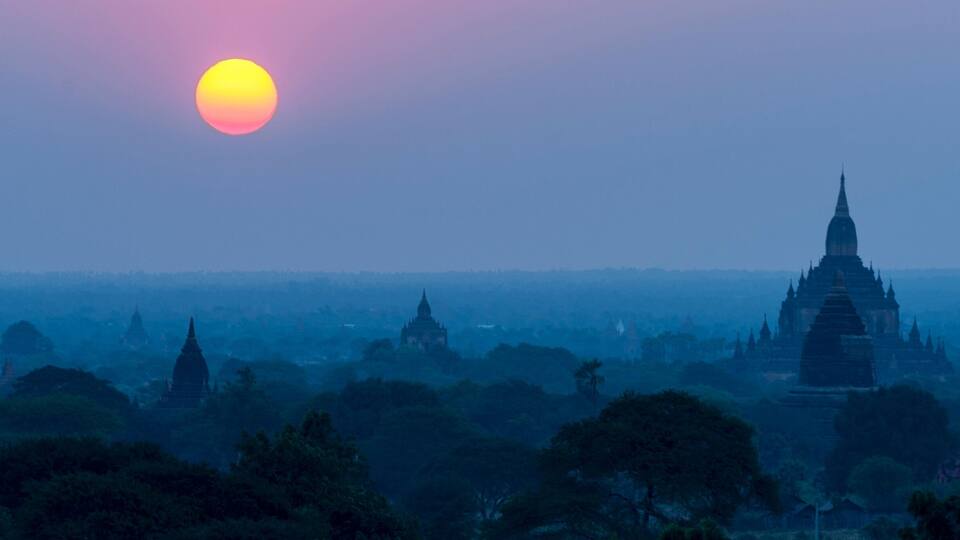 A sunset over a cityscape with numerous pagodas.