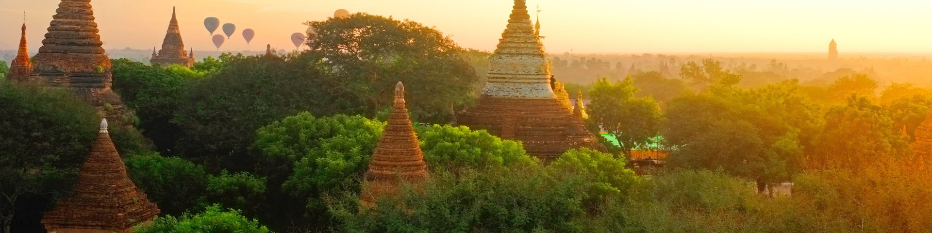 Sunrise in Bagan Archeologial Zone, Myanmar top view with hot air ballooons flying on a horizont. View from a pagoda rooftop