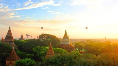 Sunrise in Bagan Archeologial Zone, Myanmar top view with hot air ballooons flying on a horizont. View from a pagoda rooftop