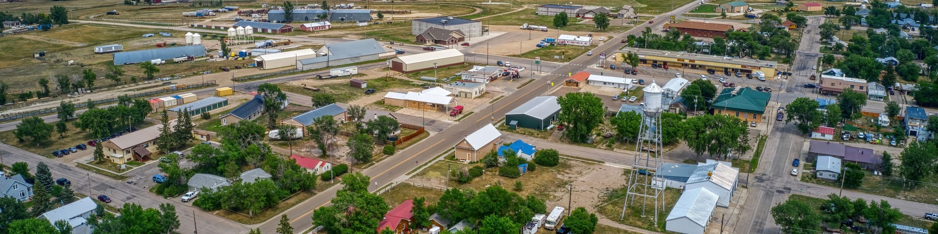 An aerial view of a small town with a mix of industrial buildings, residential houses, and green spaces.