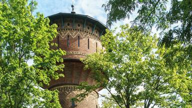 A brick tower with a dome, surrounded by trees and a grassy area.
