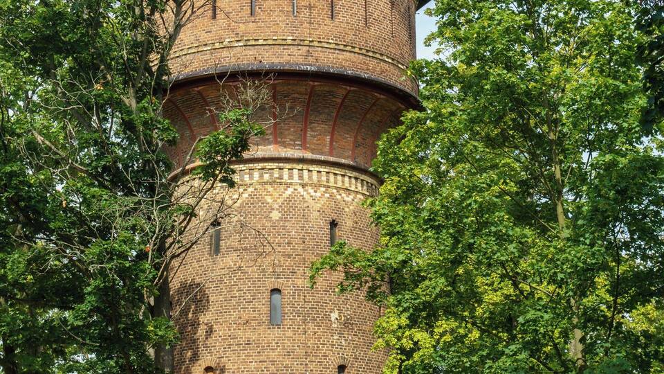 A brick tower with a conical roof surrounded by trees.