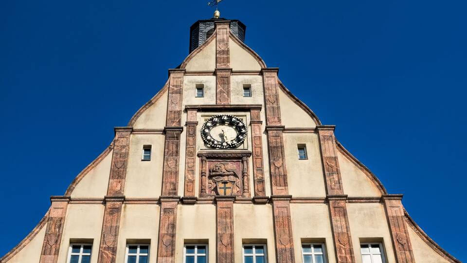 A building with a clock tower, large windows, and a clear blue sky.