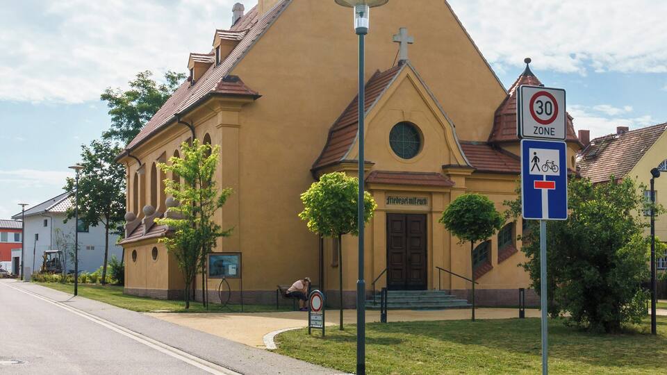 A church with a clock tower and a '30 zone' sign.