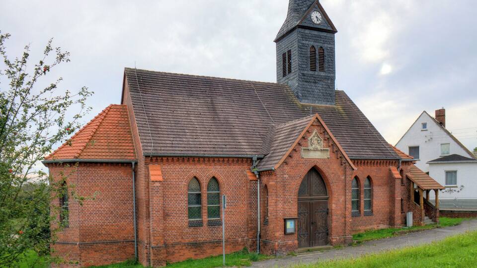A brick church with a steeple and a clock tower.