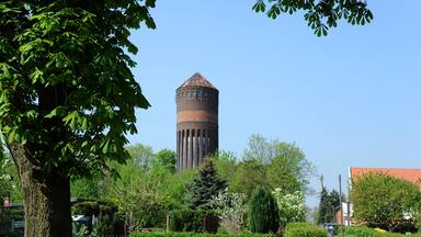 A historic water tower surrounded by lush greenery and trees.