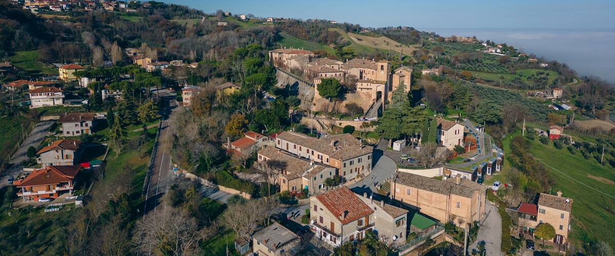 A historic town with medieval architecture, including a prominent castle, surrounded by lush greenery and rolling hills.