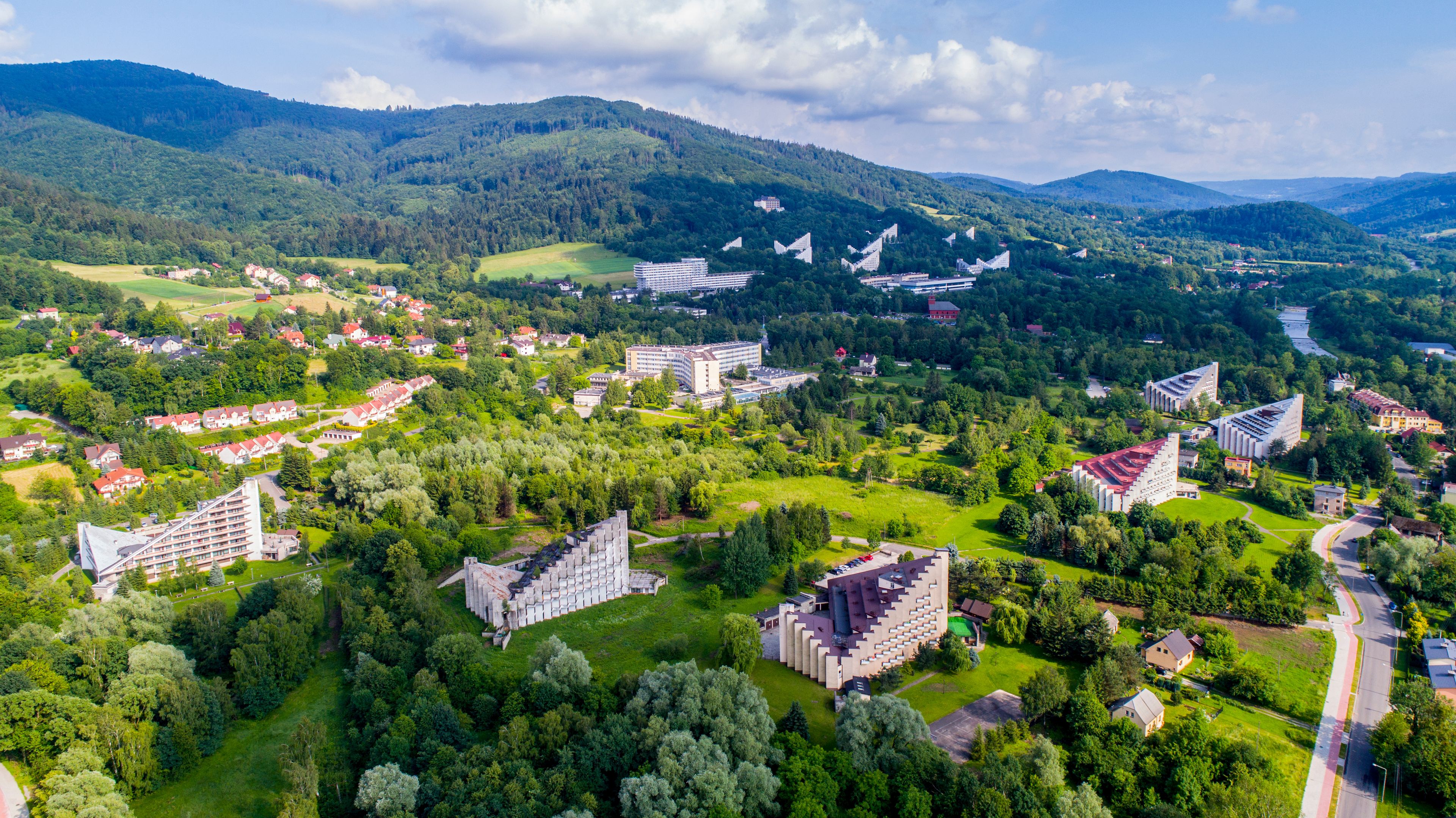 Un paisaje montañoso con zonas residenciales, campos verdes y edificios modernos.
