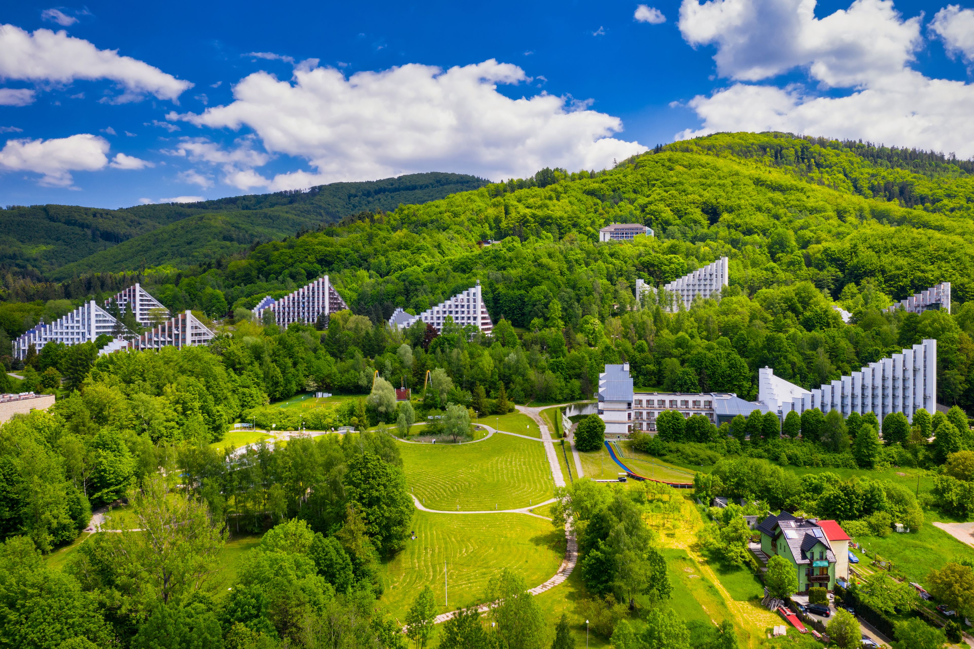 Paisaje montañoso con zona residencial que presenta arquitectura moderna en medio de abundante vegetación.