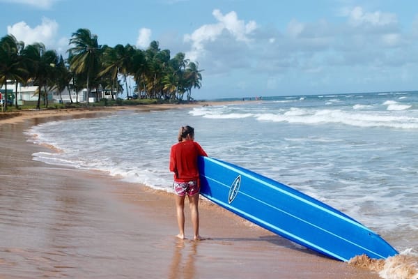 A beach with palm trees and ocean waves.