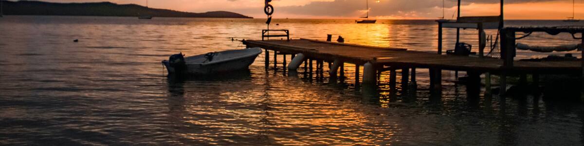 A sunset over a calm body of water with a pier and a boat docked.