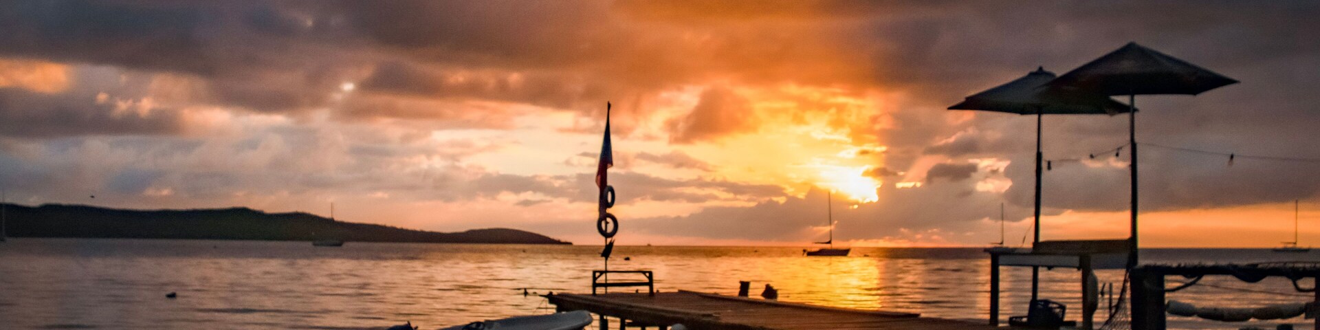 Un atardecer sobre un cuerpo de agua tranquilo con un muelle y un barco amarrado.