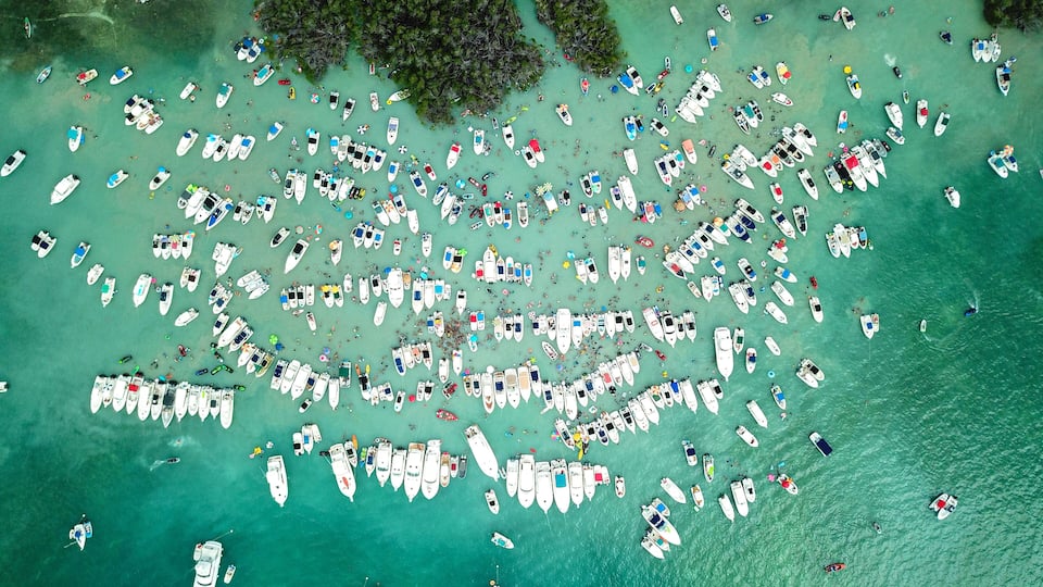 An aerial view of a crowded beach with numerous boats and people.