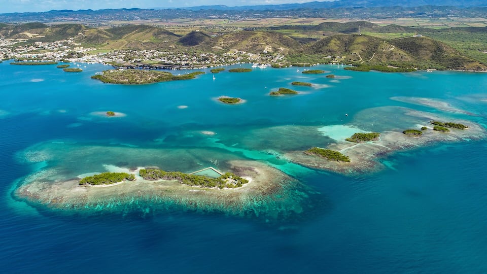 An aerial view of a coastal region with multiple small islands surrounded by clear blue waters.