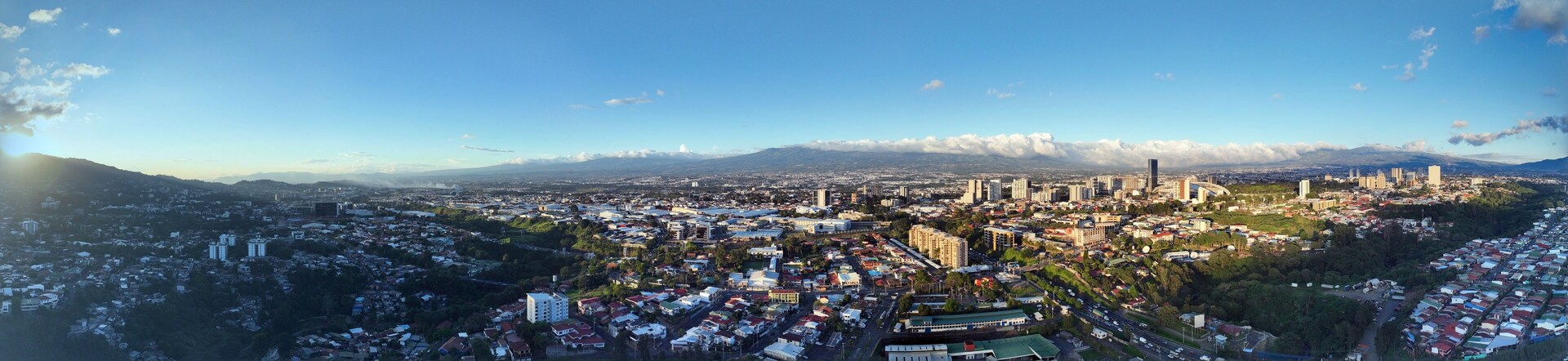 Una vista panorámica de una ciudad con una imponente cadena montañosa al fondo.