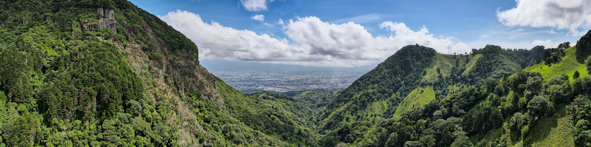 Un valle exuberante con densos bosques verdes y pronunciadas colinas.