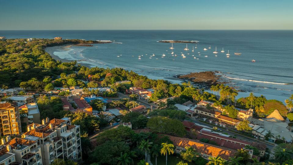 A coastal town with a beach, boats, and a bridge.