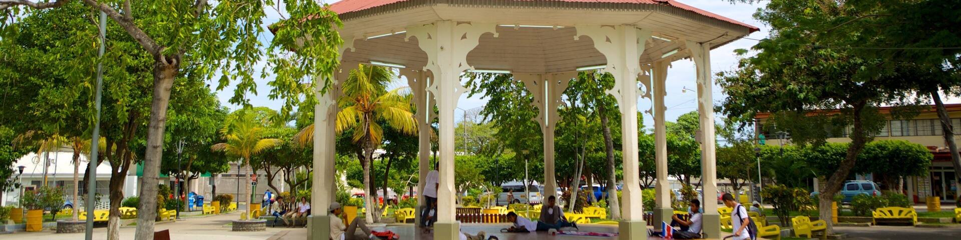 A gazebo with a red roof surrounded by trees and benches.