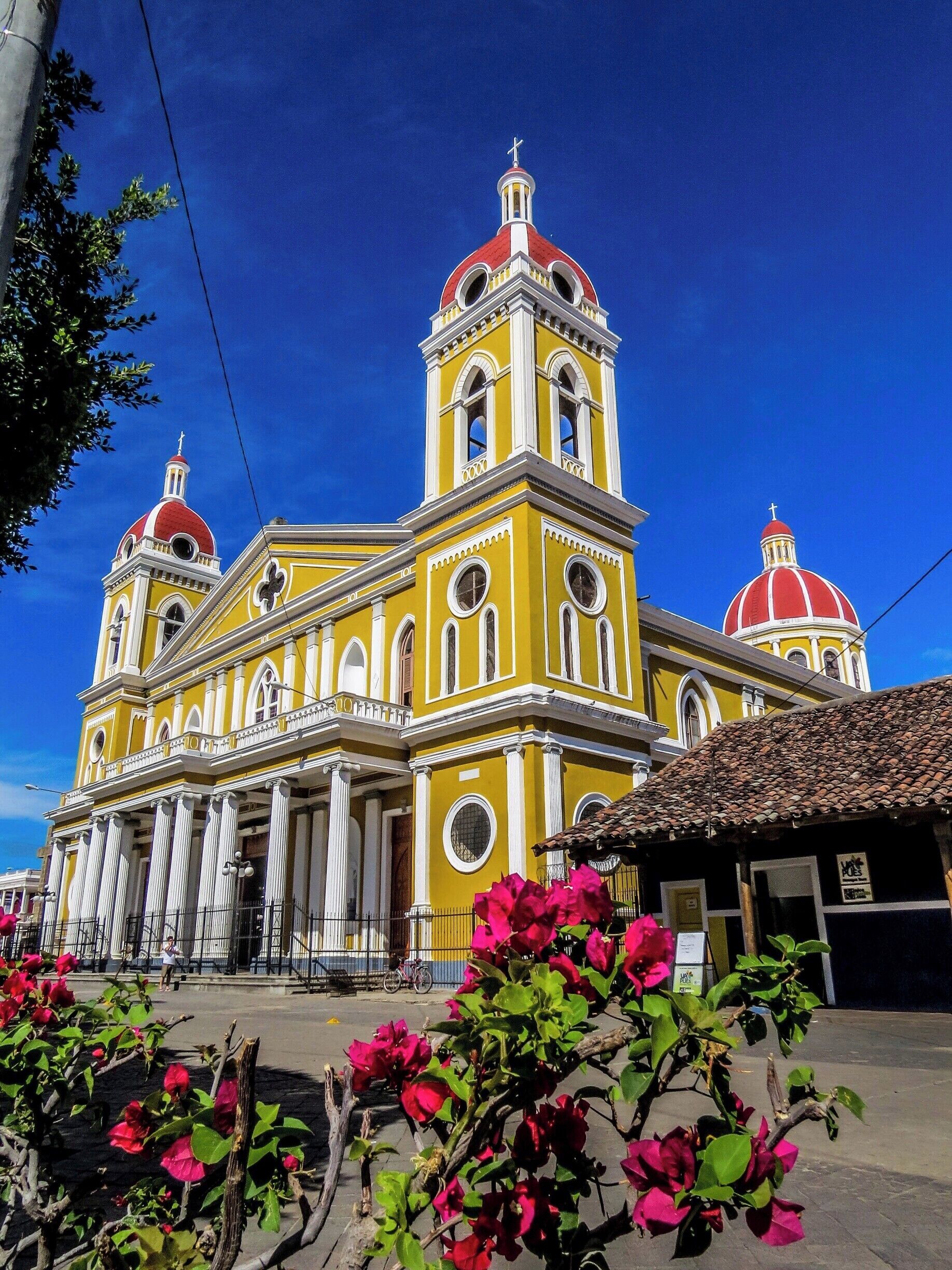 A yellow church with red domes and a cross on top.