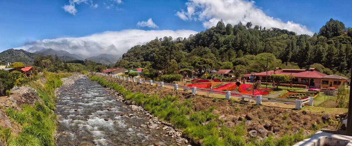 A river flowing through a valley with houses and gardens on the hillside.