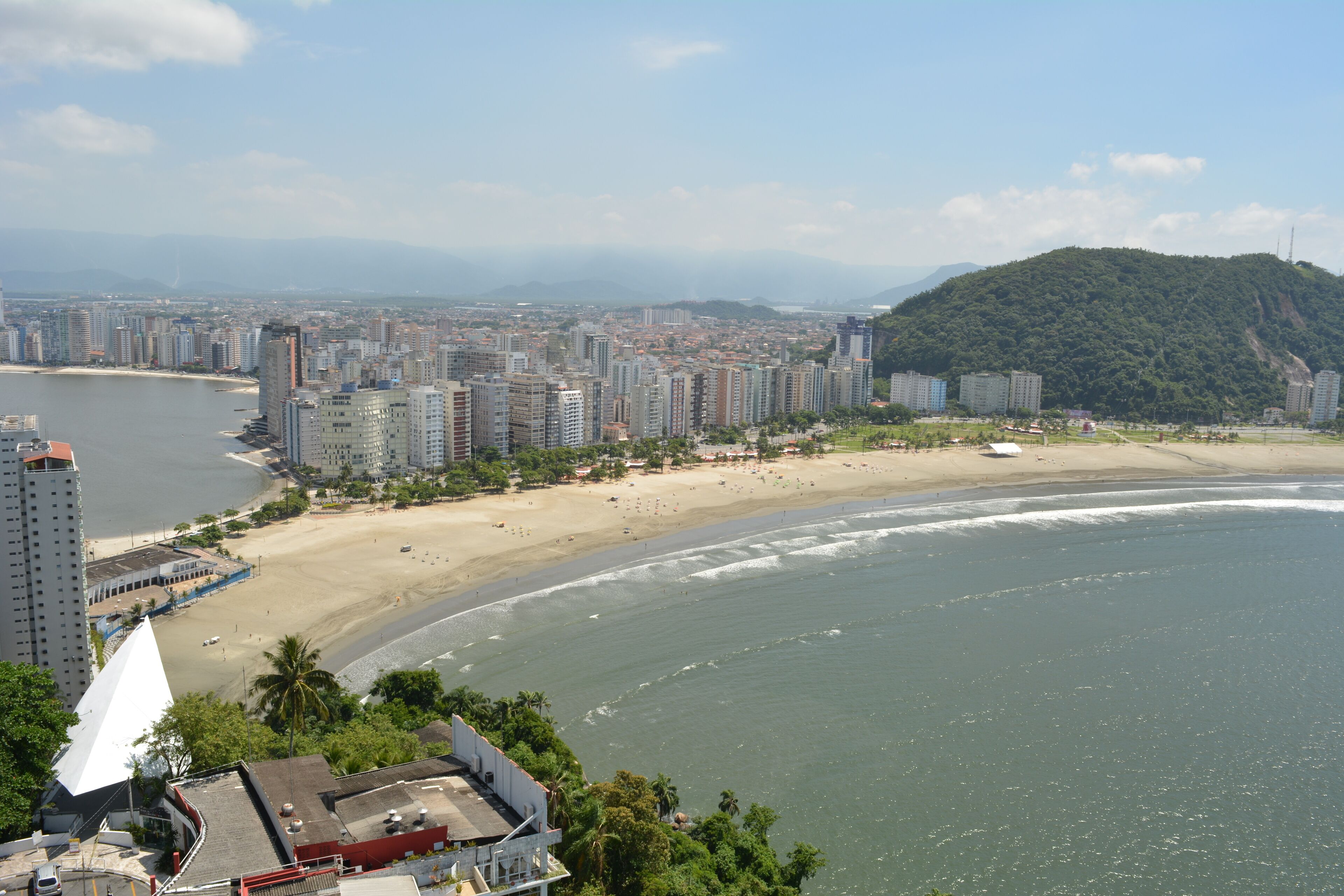 A coastal cityscape with a beach, high-rise buildings, and a mountain in the background.