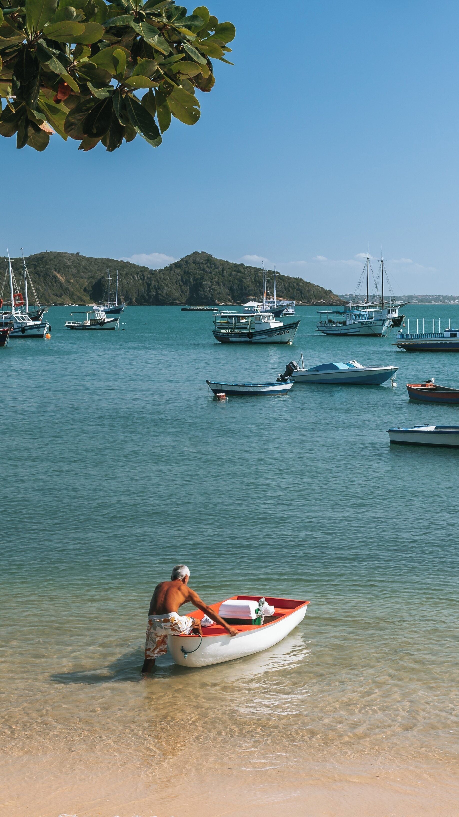 Bright day at Armacao Beach with fishing boats and a local preparing for the sea in Buzios, Rio de Janeiro